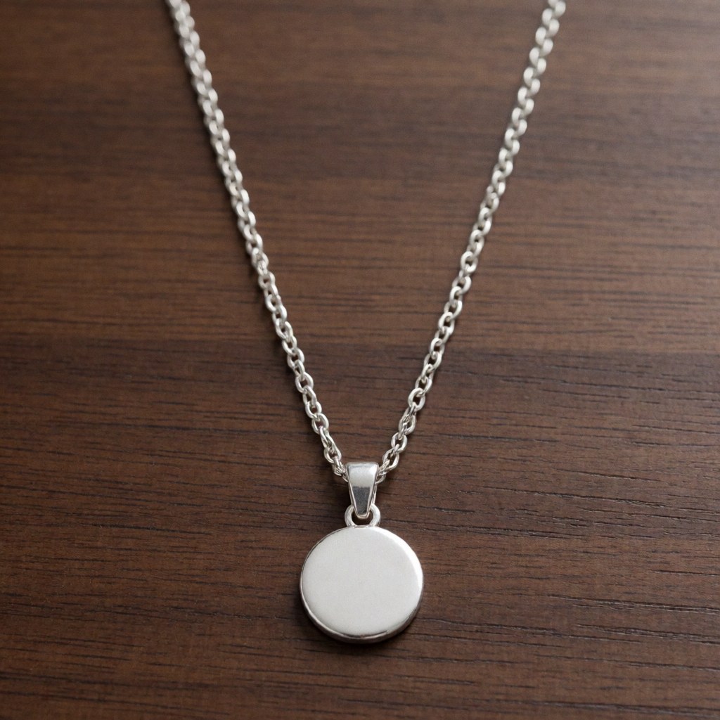 Close-up of a silver necklace featuring a round pendant resting on a wooden surface, ideal for jewelry store product displays.
