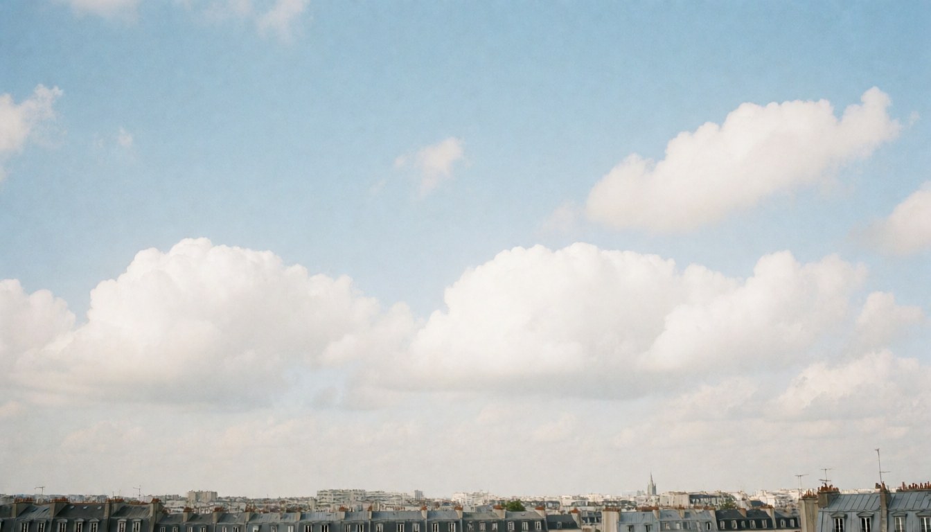 Blue sky with white clouds over the rooftops of a European city.
