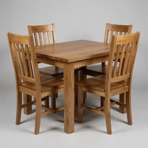 Wooden dining table with four wooden chairs against a light gray background.
