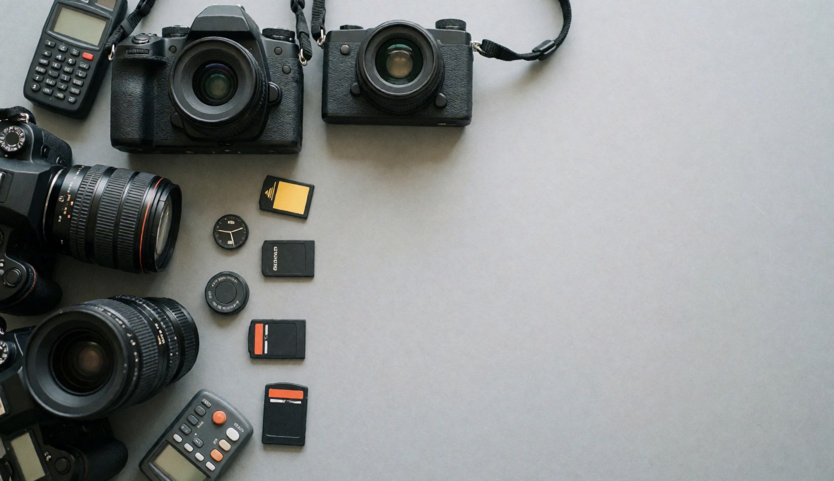 Professional photography equipment including cameras and lenses on a gray surface.
