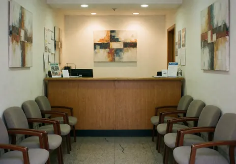 Service center reception with chairs for clients and wooden counter with computer and documents.