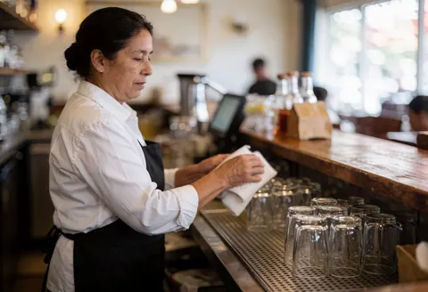 A bartender cleaning glasses on a wooden bar in a bar.