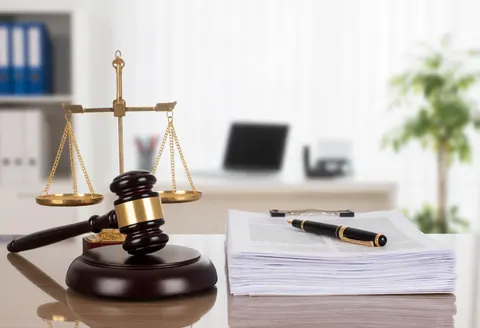 Gavel and scales of justice on an office desk with documents and a pen.