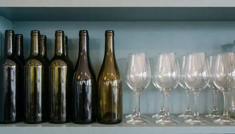 Blue and gray toned bar shelf with wine bottles and crystal glasses, serving as a text background for advertising.