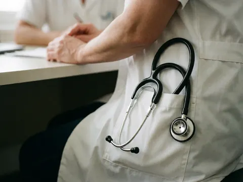 A close-up view of a stethoscope placed on the fabric of a white doctor's coat, symbolizing medical care and clinical professionalism.
