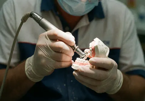 Close-up view of a dentist wearing gloves and protective gear performing precise dental polishing on a patient's teeth in a clinical setting