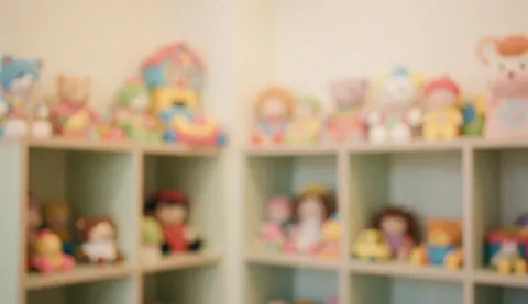 Blurred shelves with pastel dolls and toys, creating a warm, safe backdrop ideal for text overlay in children's hair salon marketing.