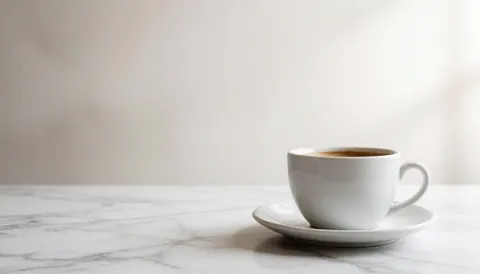 Clean white marble surface with a coffee cup, serving as a minimalist background for business use