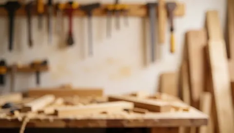 Blurred workshop background featuring carpentry tools and wooden boards, providing a warm and neutral texture ideal for text overlays and business contact information.