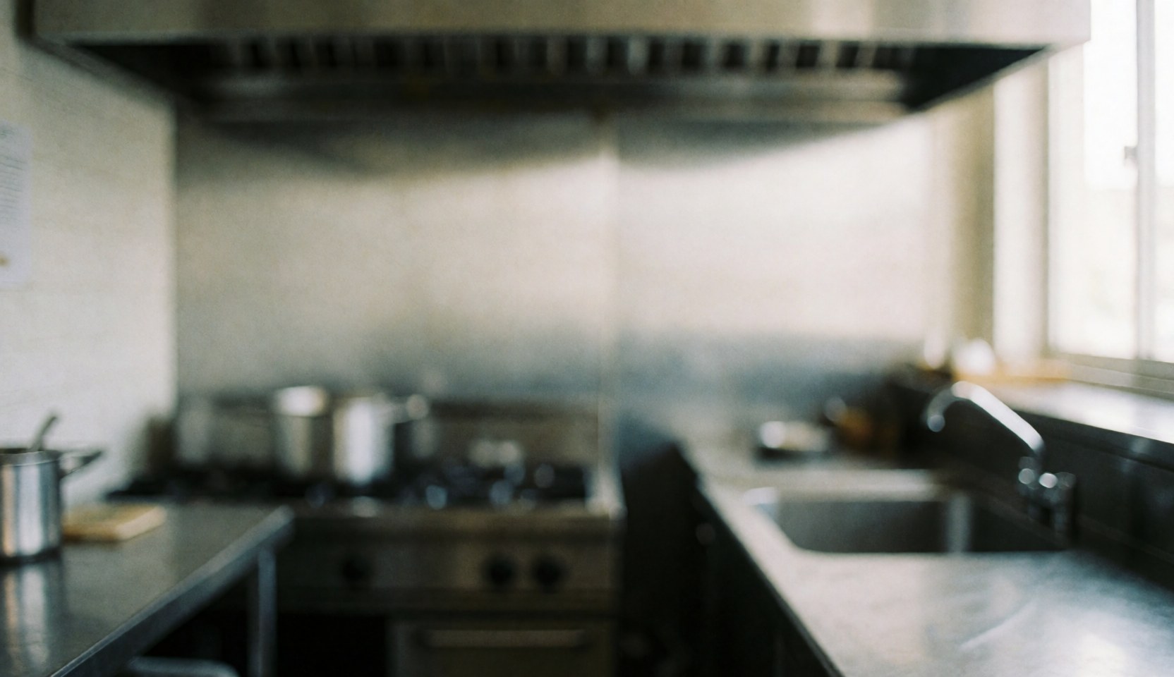 A clean, out-of-focus background suitable for adding text, featuring neutral tones and subtle hints of stainless steel surfaces typical of a professional kitchen environment.