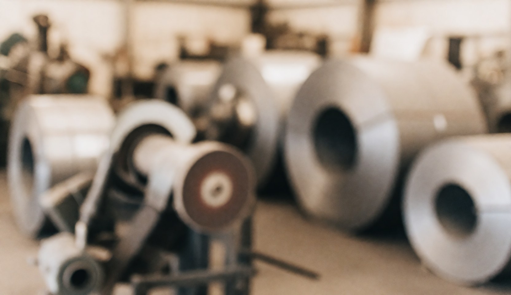Out of focus industrial steel factory background featuring steel coils and tools, suitable for commercial text overlay.