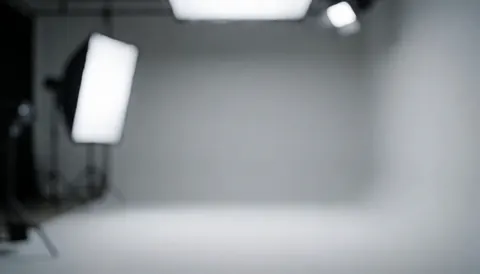 Softly lit gray studio backdrop with neutral walls, ideal for corporate portraits and business text overlays