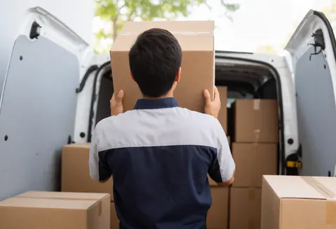 A logistics worker loading merchandise boxes into a van, illustrating service operations for entrepreneurs.