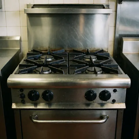 Close-up view of a stainless steel industrial gas stove with multiple burners installed in a professional commercial kitchen setting