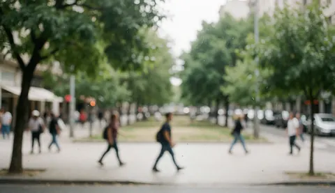 Soft focus city street scene with green trees and walking pedestrians, suitable for psychology and mental health text overlays.