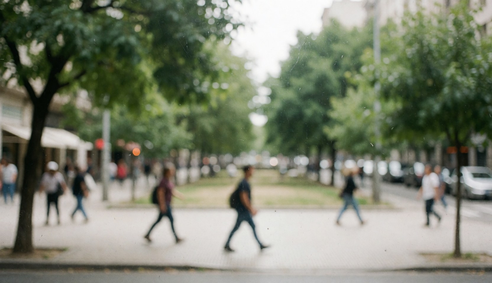 Soft focus city street scene with green trees and walking pedestrians, suitable for psychology and mental health text overlays.