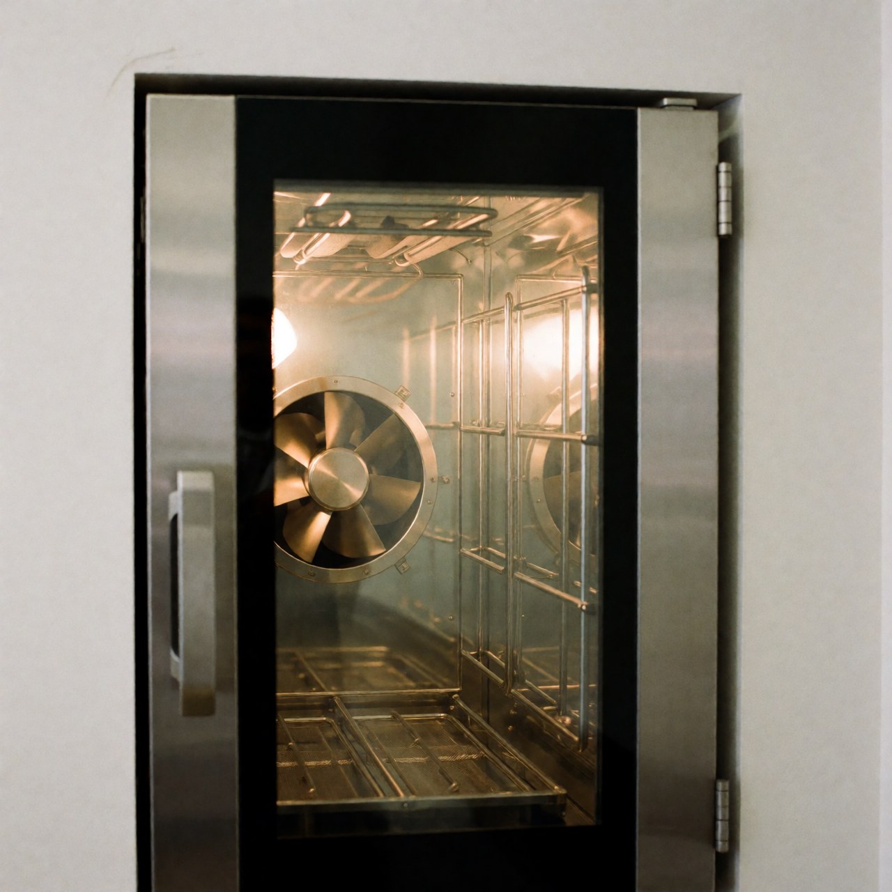 Close-up interior view of a professional stainless steel convection oven with visible heating elements and a glass door, set against a white background.