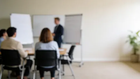 A clean white meeting room with empty chairs and a table, providing a neutral background suitable for business presentations and training materials.
