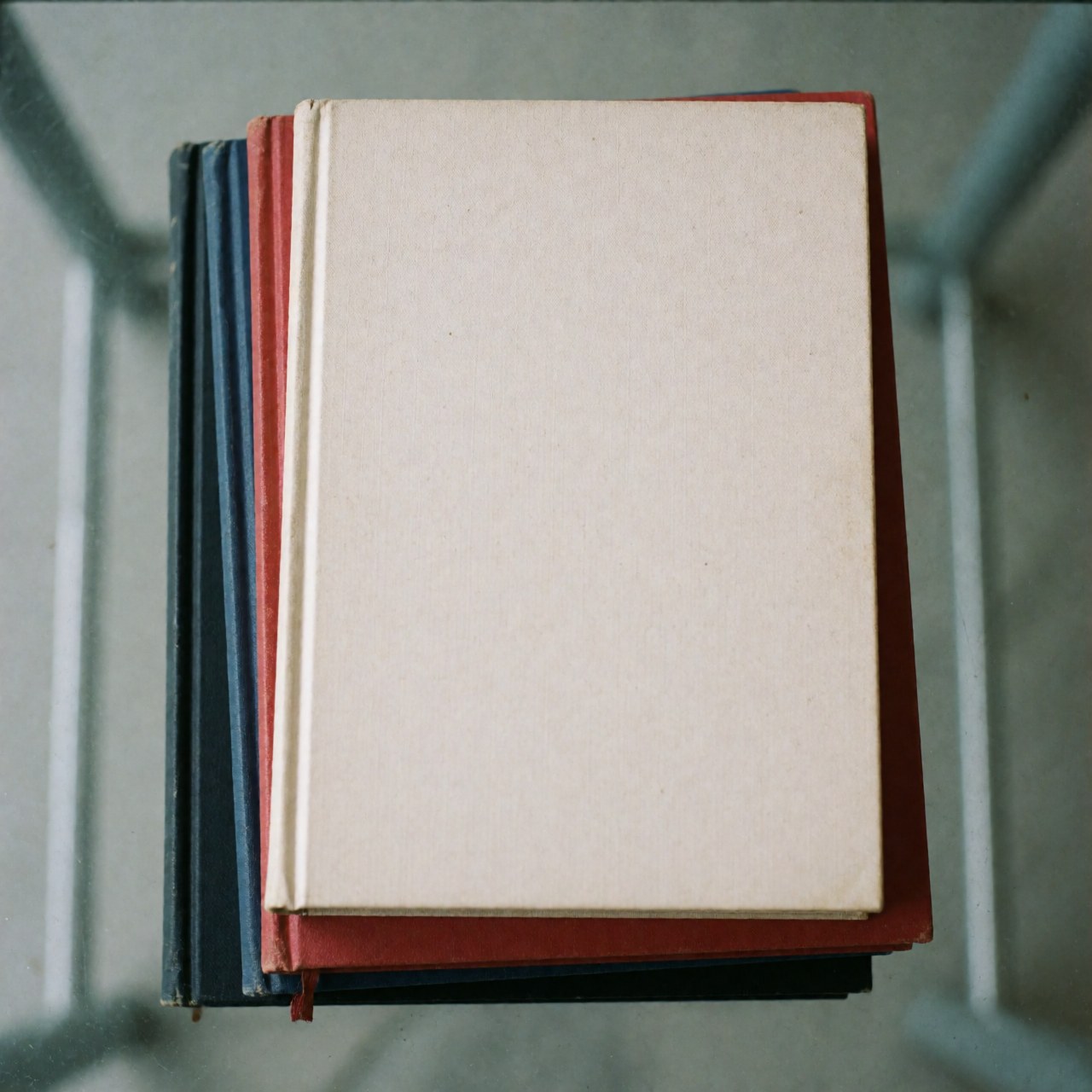 Top view of a pile of colorful university textbooks on a glass surface with even lighting, representing education and study