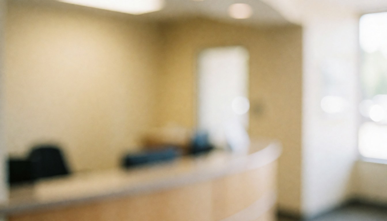 Soft focus beige walls and reception desk in a university admissions office with warm lighting, suitable for professional text overlays.