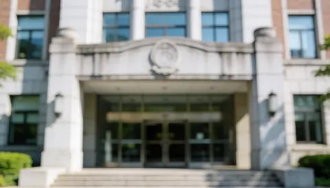 A blurred background of a university entrance featuring stone walls, windows, doors, and stairs in gray and white tones