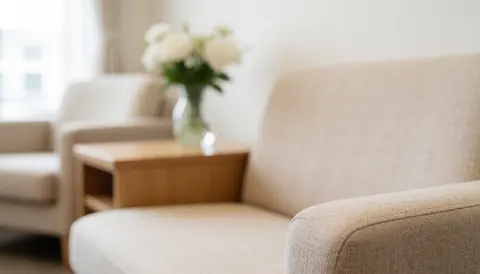 A serene waiting area featuring a beige sofa, wooden table, and floral arrangement, ideal for psychology and therapy business backgrounds.