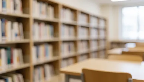 A quiet university library interior featuring rows of bookshelves, study tables, and books, serving as a calm background for educational content