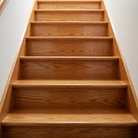 Close-up view of a restored wooden staircase with polished natural wood steps and railings in a home interior