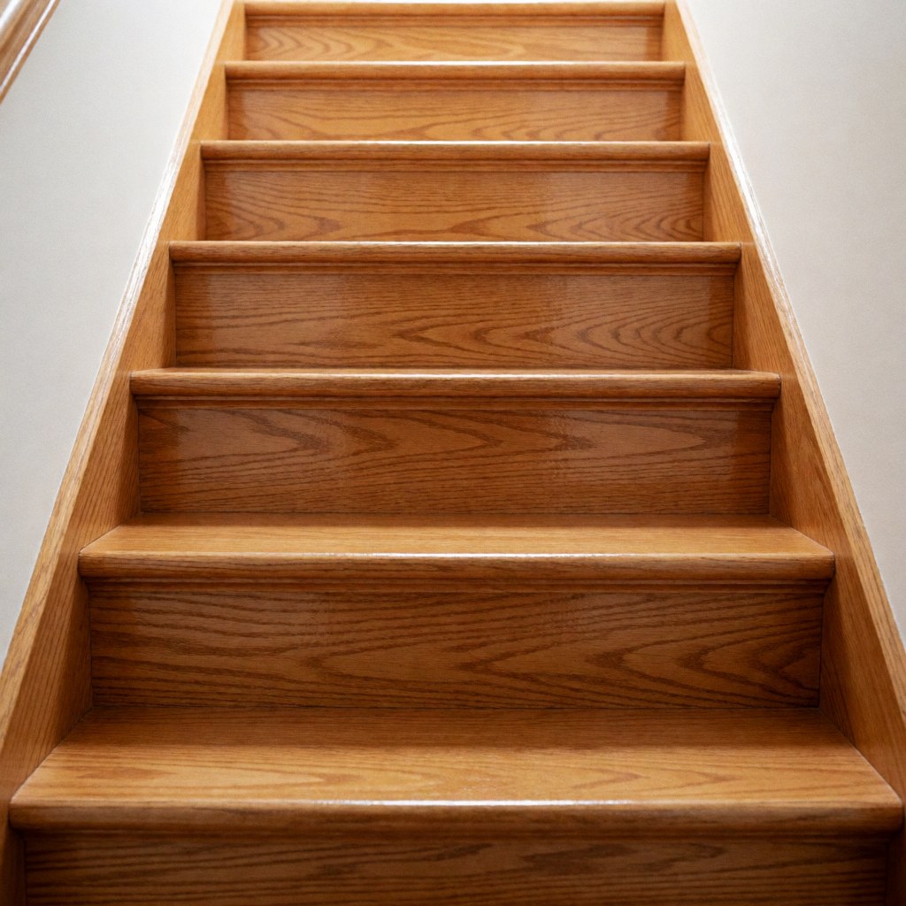 Close-up view of a restored wooden staircase with polished natural wood steps and railings in a home interior