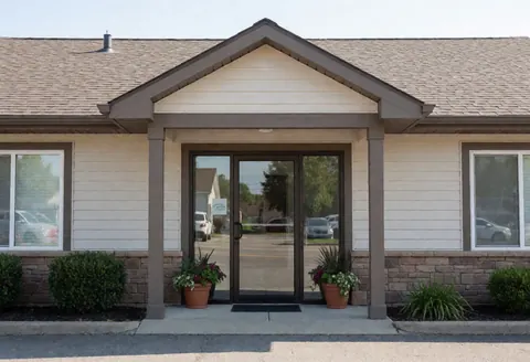 Neutral facade of a field office entrance featuring a glass door, potted plants, and stone accents for a professional business setting
