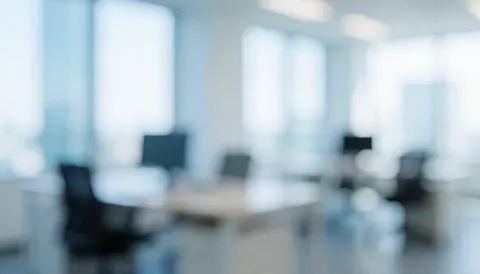 A blurred modern office interior featuring white walls, blue accents, and natural light from windows, ideal for business and human resources text backgrounds.