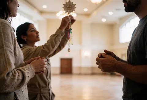 A woman adjusts a hanging ornament in an empty event hall while two people watch. Realistic wedding and event preparation scene.