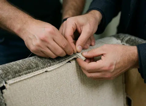 Close-up view of precise upholstery stitching on textured fabric, highlighting craftsmanship and quality materials in furniture manufacturing.