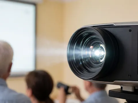Detailed close-up view of a projector lens and housing, highlighting the technology used for team meetings and business presentations in an office setting.