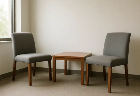 An empty professional interview room featuring a wooden table, chairs, and natural light from a window, suitable for human resources and recruitment contexts
