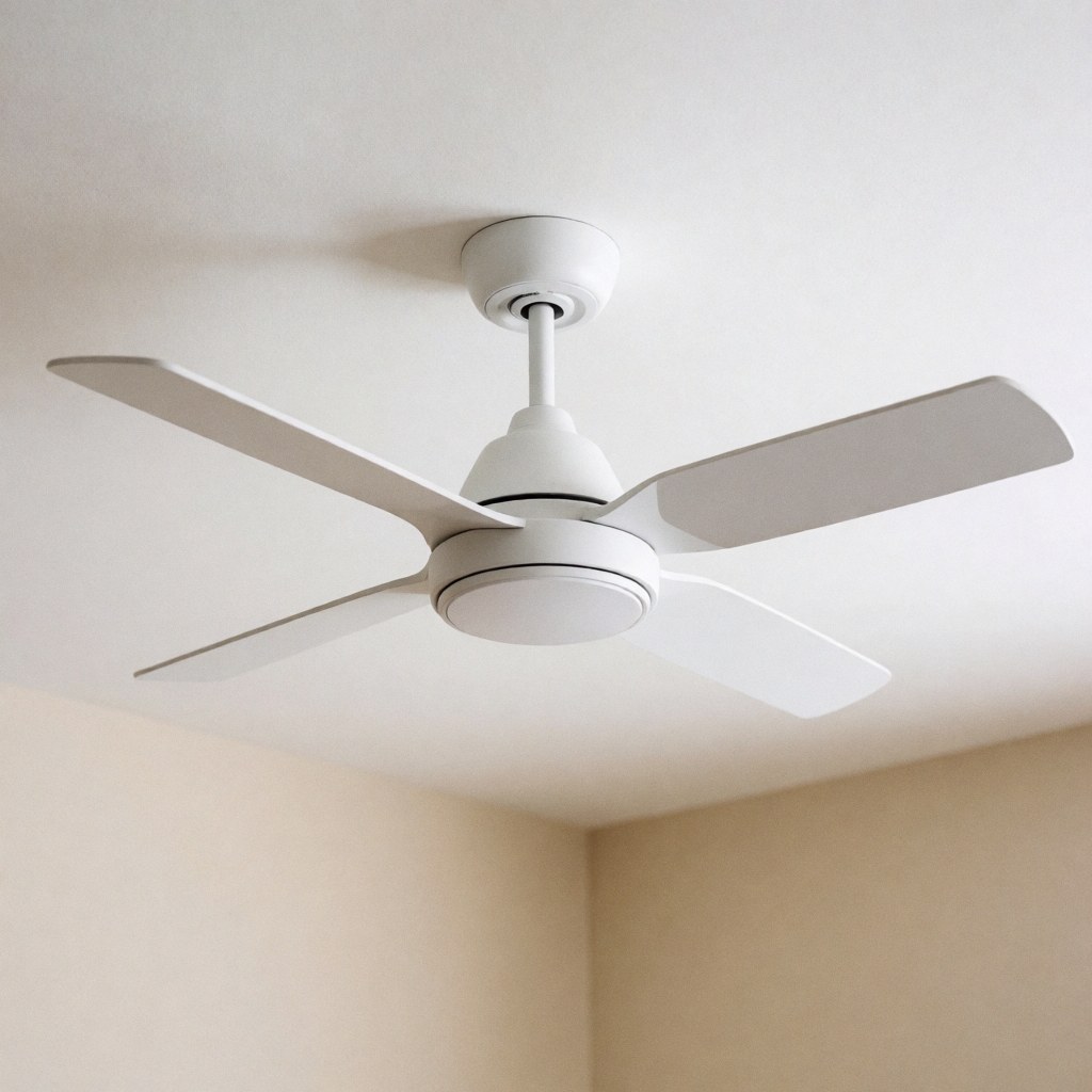 A sleek white ceiling fan mounted on a white ceiling above a beige wall, providing clean and calm modern home decor in a well-lit room.
