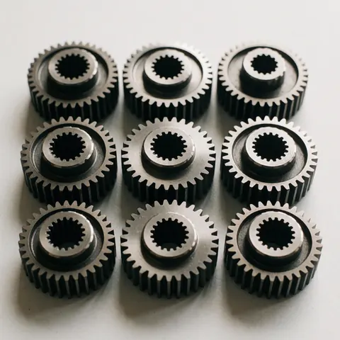 Close-up of polished precision metal gears and mechanical components arranged on a clean white background for manufacturing and engineering contexts