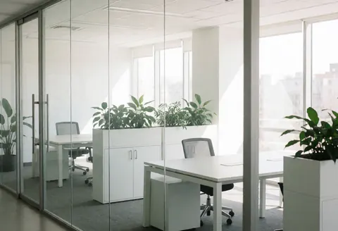 Bright and clean empty office space featuring glass walls, a desk, and green plants, ideal for software and startup business contexts