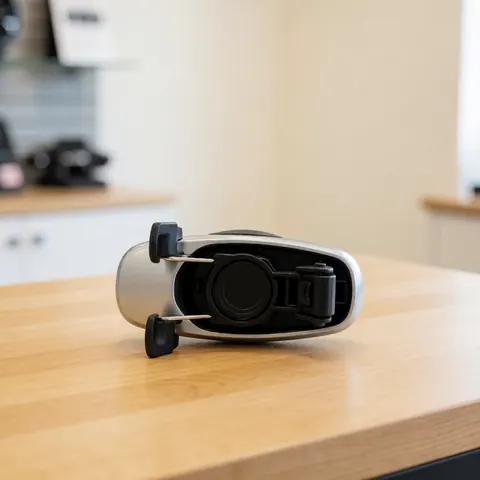 Metallic car window assembly resting on a light wooden table with a blurred kitchen background and neutral professional lighting.