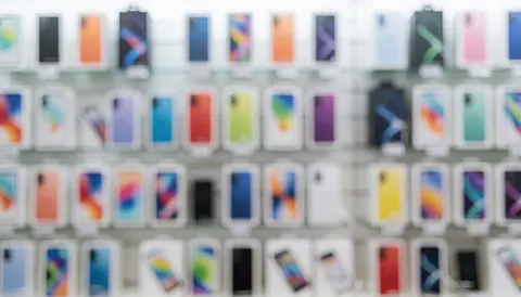 Out of focus retail display of smartphone boxes with colorful bokeh lights, serving as a vibrant background for promotional text on websites and social media.