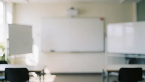 A bright, empty classroom interior featuring rows of desks and chairs, a whiteboard, and natural light, ideal for educational or language school backgrounds.