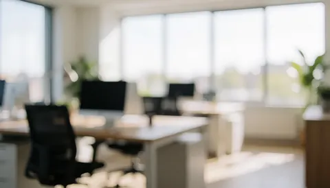 A soft focus office interior featuring a desk, chair, and window with natural light, ideal for insurance text backgrounds