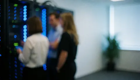 A server room illuminated by blue lights, featuring a technological and secure environment with ample space for text overlay.