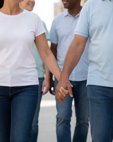 A smiling couple walks hand in hand down a busy urban street with blurred pedestrians in the background