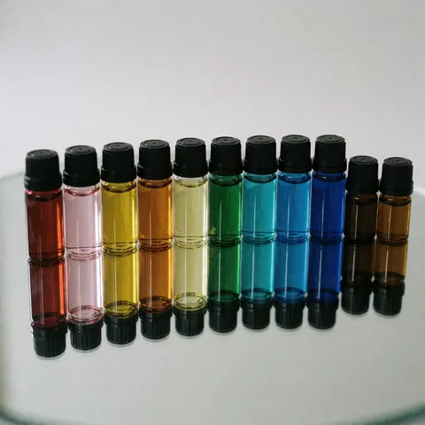 Vibrant essential oil vials arranged in a row on a reflective mirror surface with professional lighting for spa and wellness products