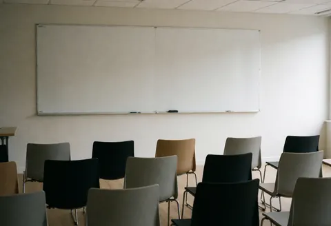 Empty modern training room featuring rows of chairs and a whiteboard, ideal for professional presentations and corporate meetings.