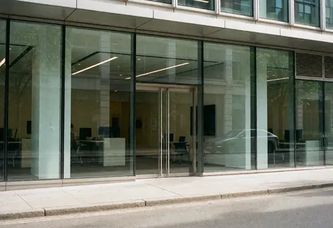 Bright modern office entrance featuring large glass doors and a sleek reception desk inside a contemporary workspace