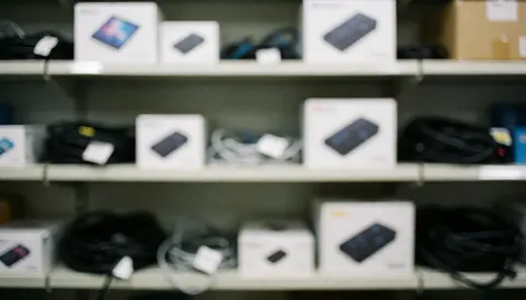 Blurred background of a technology warehouse featuring shelves, boxes, and cables, suitable for professional text overlays and business content.