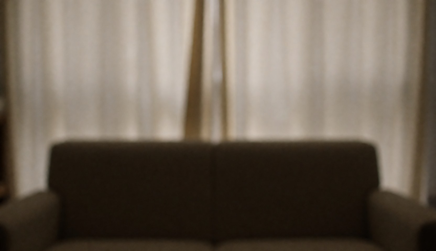 Warm and soft lighting in a therapy room featuring a sofa and curtains, ideal for professional text and content backgrounds.