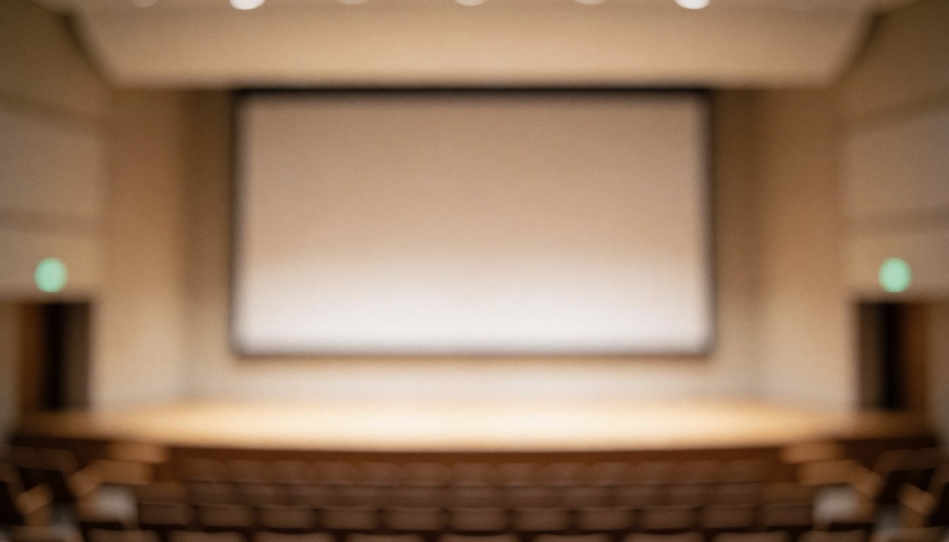 Soft focus view of a professional auditorium with a large screen and seating, serving as a clean backdrop for corporate text and business presentations.